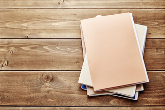 Pile of file folders with paperwork on a wooden desk.